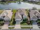 Aerial view of three houses near a lake with lush landscaping at 651 Lakescene Dr, Venice, FL 34293