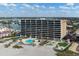 Exterior view of a high-rise building complex with pool and waterfront view on a sunny day at 840 The Esplanade N # 104, Venice, FL 34285