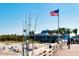 Wooden pier overlooking a sandy beach with clear blue skies and an American flag waving proudly at 840 The Esplanade N # 104, Venice, FL 34285