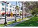 A sunny street view lined with blooming trees, shops, and a pedestrian crosswalk at 840 The Esplanade N # 104, Venice, FL 34285