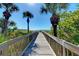 Wooden boardwalk leads to beach with palm trees and ocean views at 9895 Wingood Dr, Venice, FL 34292