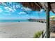 Sandy beach with pier and ocean view from under a tiki hut at 9895 Wingood Dr, Venice, FL 34292
