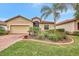 Tan single-story house with a brick driveway and landscaped yard at 9895 Wingood Dr, Venice, FL 34292