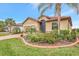 Single-story house with tan exterior, red tile roof, and landscaping at 9895 Wingood Dr, Venice, FL 34292