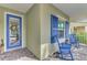 Inviting front porch with blue rocking chairs and a blue door at 12386 Sagewood Dr, Venice, FL 34293
