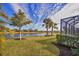 Landscaped backyard with lake view, lush lawn, and palm trees at 13836 Karina St, Venice, FL 34293