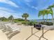 Community patio with lounge chairs, tables, and a grill overlooking the water at 1640 Stickney Point Rd # 202, Sarasota, FL 34231