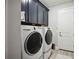 Laundry room with washer, dryer, and dark cabinets at 19854 Bridgetown Loop, Venice, FL 34293