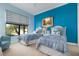 Bright bedroom with two twin beds, blue accent wall, and view of the backyard at 23402 Copperleaf Dr, Venice, FL 34293