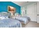 Bedroom with two twin beds, blue accent wall, and access to a bathroom at 23402 Copperleaf Dr, Venice, FL 34293