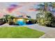 Single story home with a landscaped yard, attached garage, and palm trees at sunset at 237 San Marco Dr, Venice, FL 34285