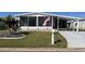 Single-wide mobile home with carport, screened porch, and landscaped yard at 28 Castaway Ct, North Port, FL 34287
