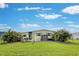 Rear view of mobile home with lawn, palm trees, and patio furniture at 3022 Audubon Ave, Englewood, FL 34224