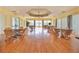 A clubhouse interior with wood floors, tables, chairs, window coverings, and a ceiling fan at 335 Sunset Lake Blvd, Venice, FL 34292