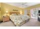 King-size bedroom with tropical bedding, ceiling fan, and access to balcony at 458 Cerromar Rd # 483, Venice, FL 34293