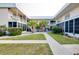 Two-story condo building with lush landscaping and walkway at 460 Base E Ave # 122, Venice, FL 34285
