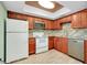 Modern kitchen with wood cabinets, granite counters, and white appliances at 460 Base E Ave # 122, Venice, FL 34285