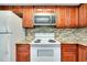 Modern kitchen with wood cabinets, granite counters, and white appliances at 460 Base E Ave # 122, Venice, FL 34285
