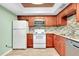 Modern kitchen with wood cabinets, granite counters, and white appliances at 460 Base E Ave # 122, Venice, FL 34285