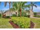 Tan house with lush landscaping, palm trees, and brick driveway at 5561 White Ibis Dr, North Port, FL 34287