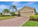 Tan house with a beige three-car garage and landscaping at 5561 White Ibis Dr, North Port, FL 34287