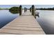 Long wooden dock on calm water with a boat at the end at 842 Linden Rd, Venice, FL 34293