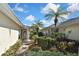 Side entrance to villa with tropical landscaping and pathway at 1104 Auburn Cove Cir, Venice, FL 34292