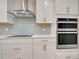 Close up view of kitchen with stainless steel appliances, sleek white cabinets, and modern backsplash at 11842 Sistine Ln, Venice, FL 34293