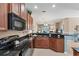 Modern kitchen featuring granite countertops, dark wood cabinets, and black appliances at 13542 Abercrombie Dr, Englewood, FL 34223