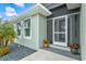 Stylish home exterior with open louvers, potted plants, gravel landscaping, and a screened entry door at 14098 Baracoa Ln, Port Charlotte, FL 33981