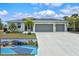 Inviting home featuring a spacious three-car garage and beautiful landscaping, including palm trees and a private backyard court at 14098 Baracoa Ln, Port Charlotte, FL 33981