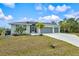 Light green house with 3-car garage and palm trees at 14098 Baracoa Ln, Port Charlotte, FL 33981