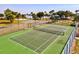 Outdoor tennis court with surrounding fences and greenery, complemented by nearby playground and lake at 14098 Baracoa Ln, Port Charlotte, FL 33981