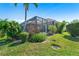 The backyard of the home features a screened pool and patio area surrounded by mature trees and lush green grass at 1721 Dogleg Dr, Venice, FL 34285