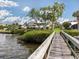 Backyard view featuring manicured lawn, dock, and lush landscaping at 1784 Bayshore Dr, Englewood, FL 34223