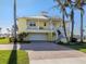 Beautiful yellow two-story home featuring a metal roof, covered balcony, and a brick driveway at 1784 Bayshore Dr, Englewood, FL 34223