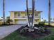Charming yellow two-story home with a metal roof, covered balcony, and tropical landscaping at 1784 Bayshore Dr, Englewood, FL 34223