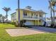 Inviting two-story yellow home with a white metal roof, covered balcony, and brick paver driveway at 1784 Bayshore Dr, Englewood, FL 34223