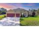 A charming home boasts a red two-car garage and meticulously manicured landscaping at 2737 Cottage Ln, North Port, FL 34286