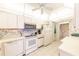 Bright kitchen featuring white cabinetry, appliances, and a tray ceiling at 301 Pinebrook Club Dr # 1, Venice, FL 34285