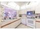 Bright kitchen featuring white cabinetry, appliances, a breakfast bar, and view to living area at 301 Pinebrook Club Dr # 1, Venice, FL 34285