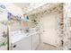 Efficient laundry room with white appliances, storage shelves, and charming floral wallpaper at 301 Pinebrook Club Dr # 1, Venice, FL 34285