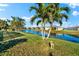 Scenic backyard with lush lawn, palm trees and picturesque lake view at 4264 Wordsworth Way, Venice, FL 34293