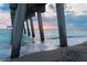 Stunning sunset view from under a pier, showcasing the ocean and sandy beach at 4264 Wordsworth Way, Venice, FL 34293