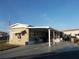 Tan mobile home with carport and American flag at 476 Boxwood Dr, Venice, FL 34285