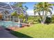 Landscaped backyard with lush lawn, palm trees, and a screened pool at 49 Perimeter Dr, Englewood, FL 34223