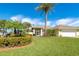 Bright yellow house with palm trees, lush landscaping, and a large driveway at 49 Perimeter Dr, Englewood, FL 34223
