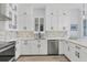 Modern white kitchen with stainless steel appliances and stylish backsplash at 503 N Tamiami Trl # 301, Venice, FL 34285