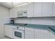 White cabinets, teal countertops, and built-in microwave at 627 Alhambra Rd # 601, Venice, FL 34285