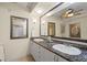 Spacious bathroom featuring double sinks with granite countertops, a large mirror, and a ceiling fan at 9203 Griggs Rd # B202, Englewood, FL 34224
